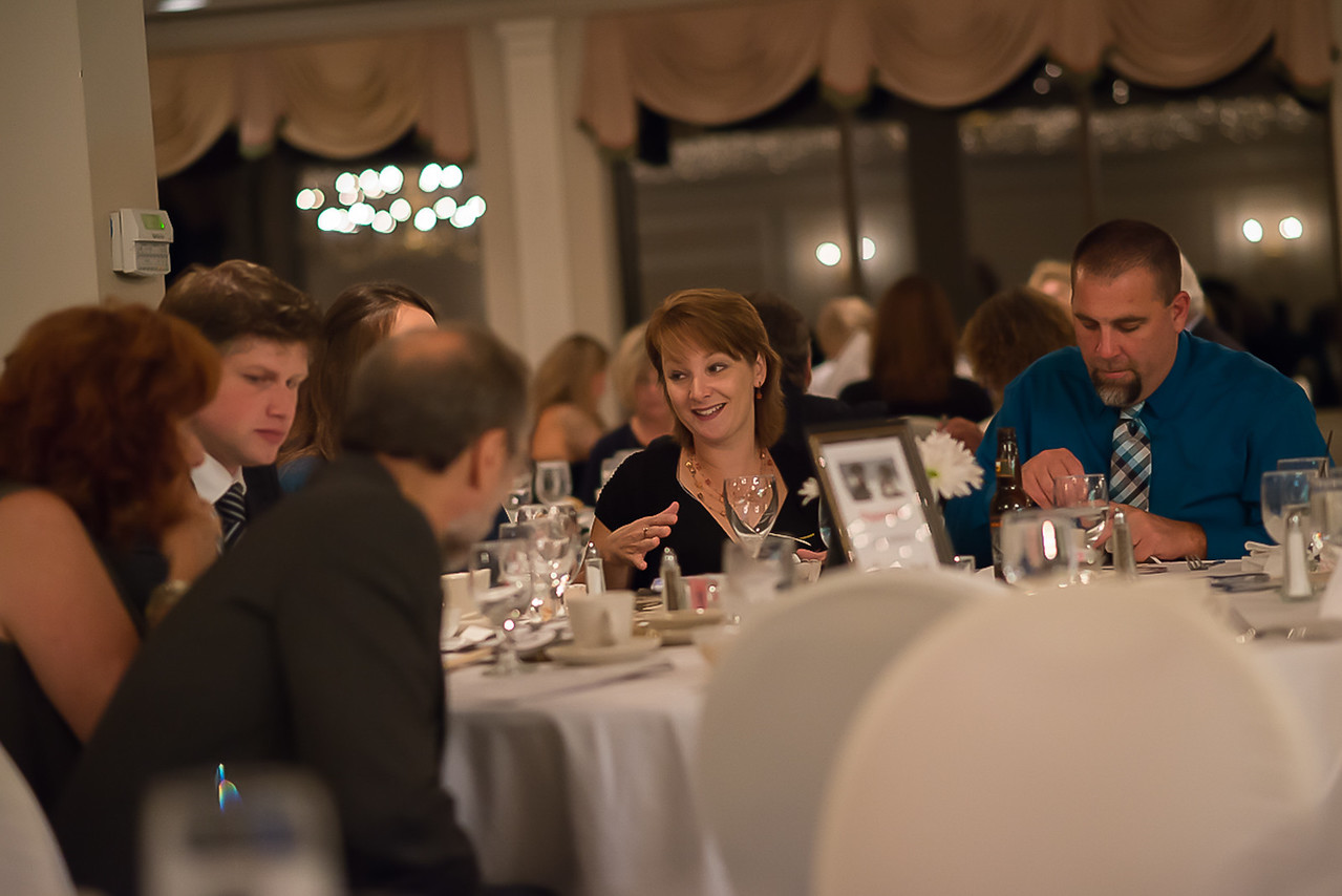 A woman sits at a dinner table talking amongst others at Unleash Your Heart Gala .